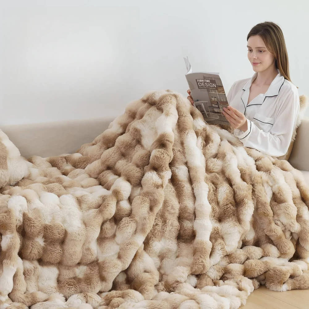 SweeTee Bubble Fleece Blanket in blush pink, shown draped on a bed